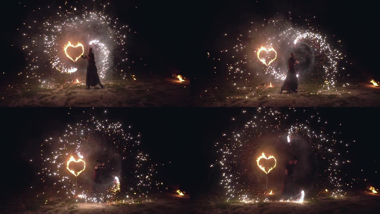 男人艺术家在他的手中扭转火物体闪闪发光的火表演，背景是燃烧的心