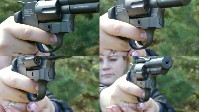 带枪的女孩带领目标。女人射击气动手枪。女性手中的气动左轮手枪。美甲特写。