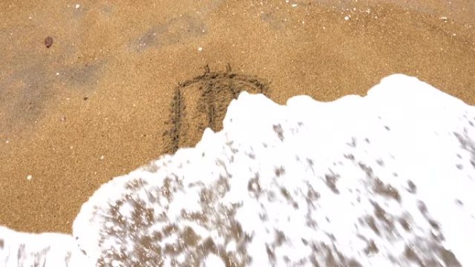 写在沙子上的比特币加密货币标志。海浪冲走了比特币的铭文