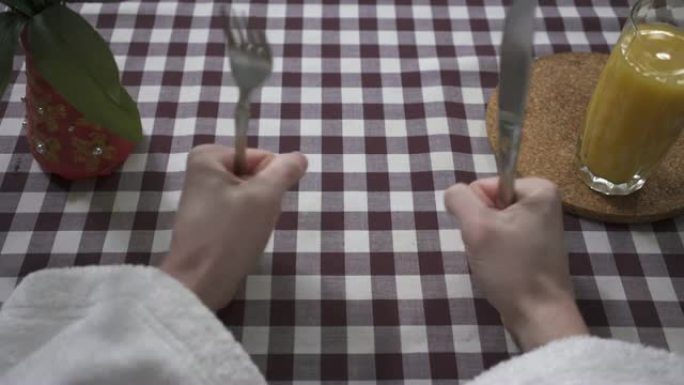 男人用叉子和刀子将鸡蛋放在盘子上。