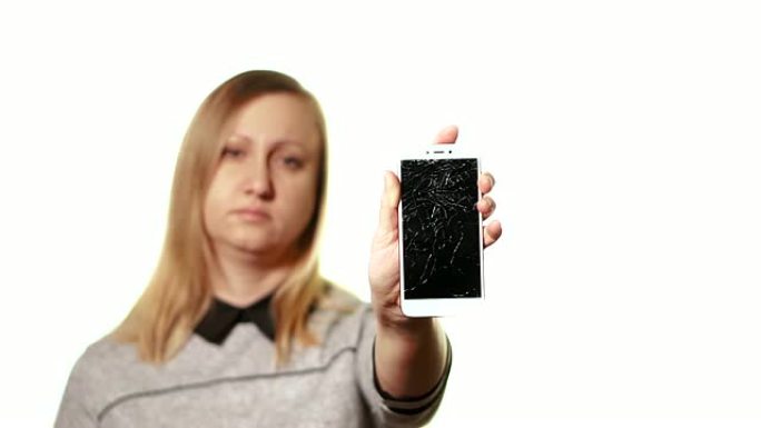 坏掉的小工具的概念。沮丧而疲惫的中年妇女拿着智能手机在他面前，他的屏幕坏了。