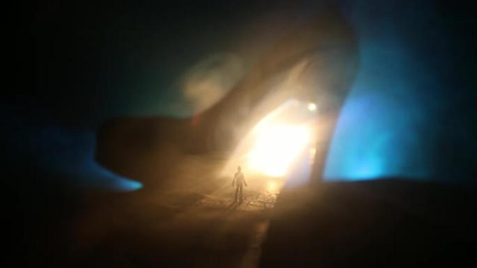 艺术品装饰。一个男人站在路中间的轮廓，在一个雾蒙蒙的夜晚，穿着巨大的高跟鞋。女性权力或女性统治概念。