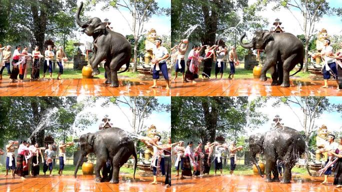 慢动作泼水节-美女和男人穿着传统泰国服装在寺庙背景上泼水