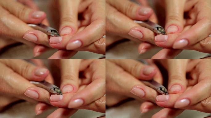 美甲师用指甲剪去除女性指甲角质层的特写镜头。