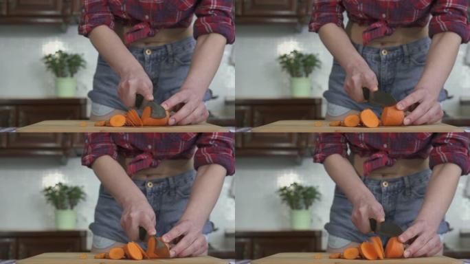 在现代厨房的背景下，穿着格子衬衫和短裤在木板上切成胡萝卜的不被认可的苗条女孩。