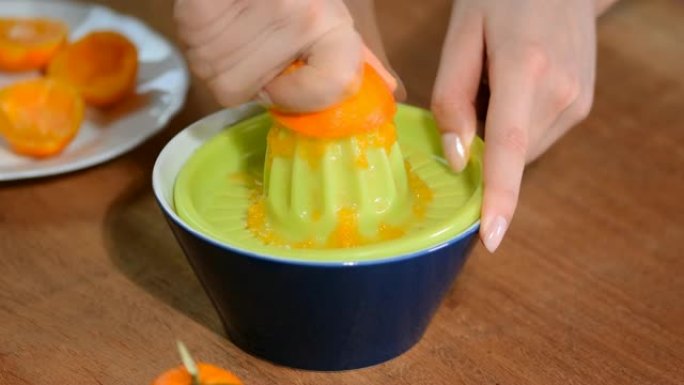 女性的手从橘子里榨汁。