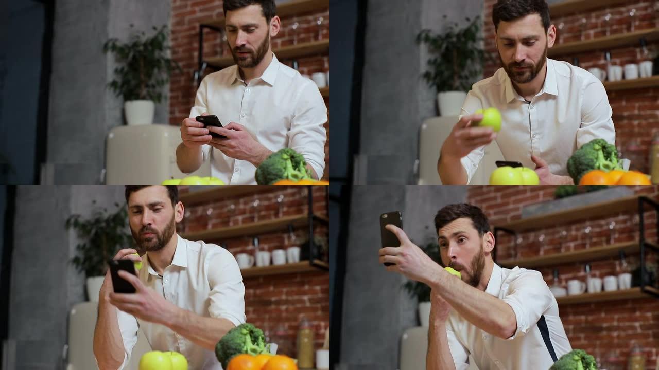 男人在家里厨房用手机浏览。英俊的年轻人浏览智能手机微笑快乐。一个人吃了一个苹果，然后拍照。