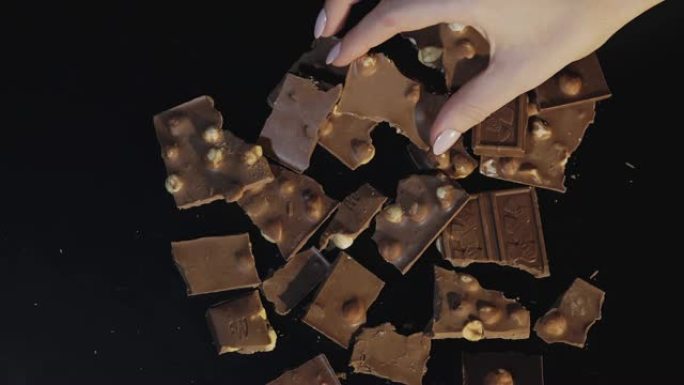 女人的手从一堆巧克力中拿出一块巧克力棒。慢动作