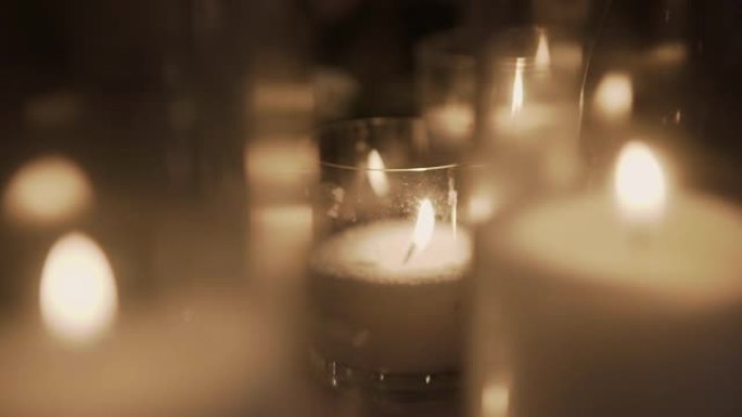 在模糊的背景上，玻璃烛台上燃烧着装饰性的蜡烛
