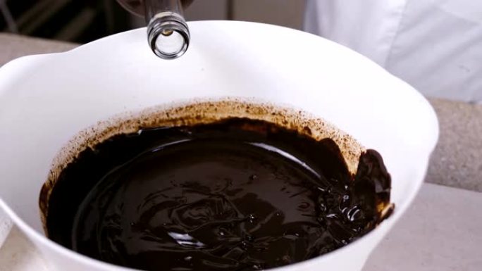 将甘油倒入白色碗中的液态黑巧克力中并混合。