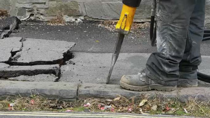 工人在街上用压缩机钻混凝土。