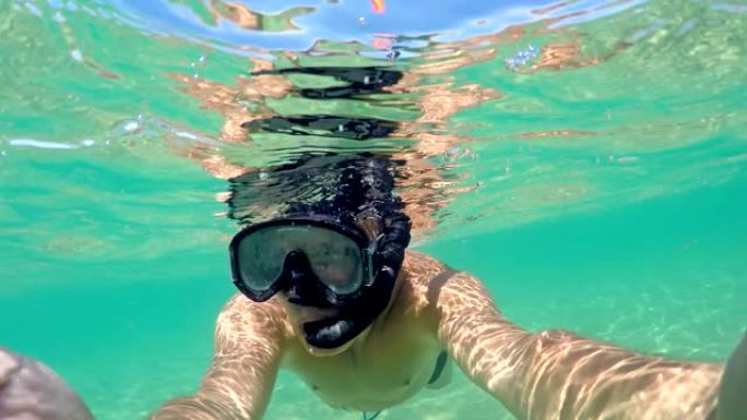 半水下自拍从男子潜水用浮潜面具。加勒比海清洁绿松石水，gopro圆顶拍摄