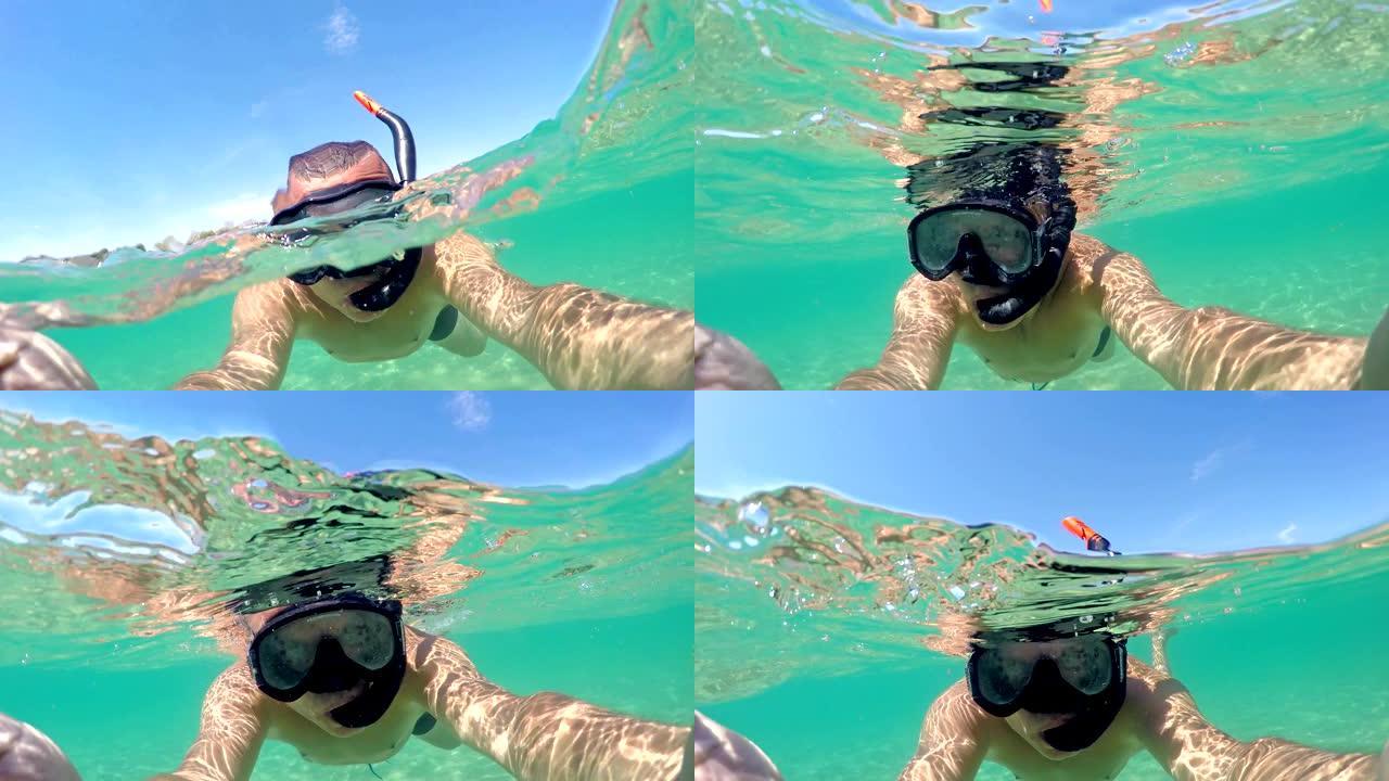 半水下自拍从男子潜水用浮潜面具。加勒比海清洁绿松石水，gopro圆顶拍摄