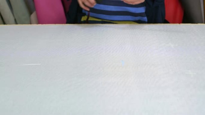 一家家具厂的老妇人正在用塞子测量并标记沙发上的灰色材料