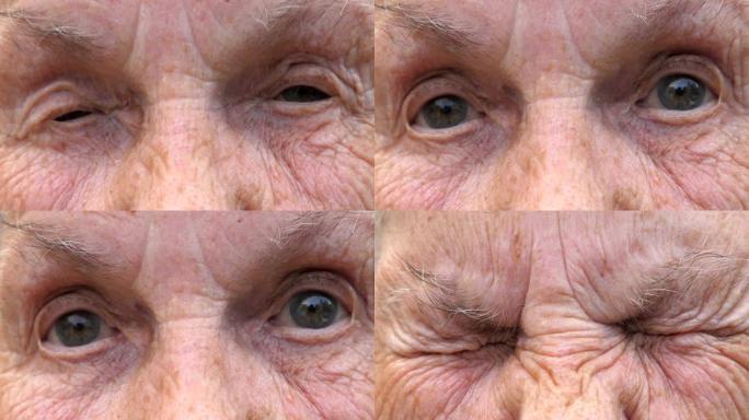 成熟女人的肖像拧起灰色的眼睛，然后睁开。老祖母皱着眉头的脸带着悲伤的目光看着镜头。高级女士的悲伤表情