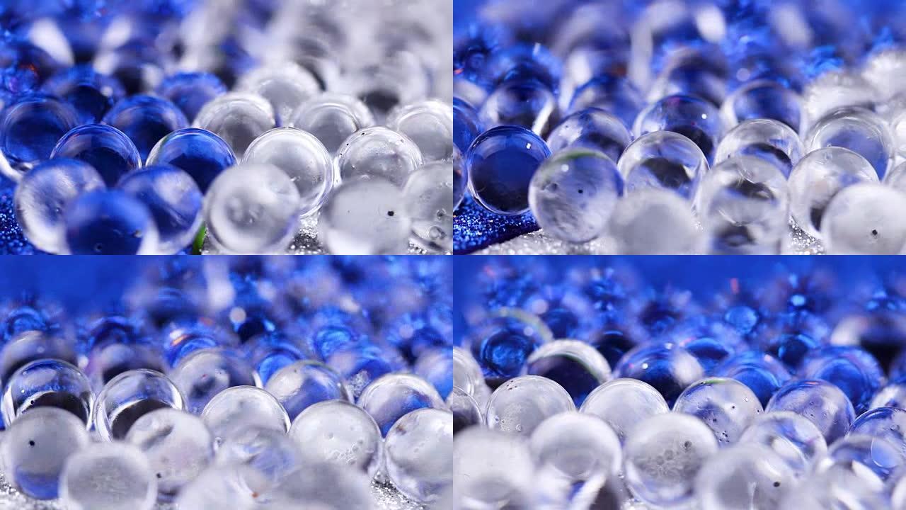 水凝胶球在蓝色和银色表面上旋转。特写宏。