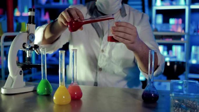 将溶液从烧瓶中倒入化学实验室的玻璃烧杯中。对液体进行科学体验。