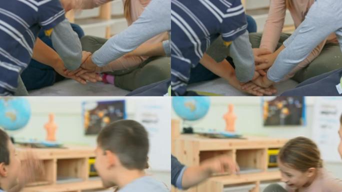 孩子们和老师坐在教室的地板上，手把手加油