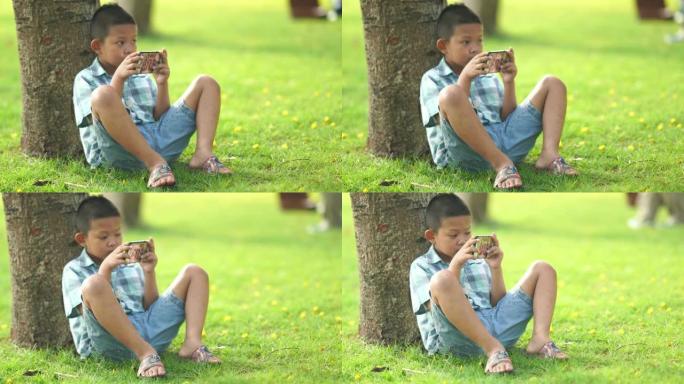 亚洲男孩在花园里使用数字游戏和智能手机