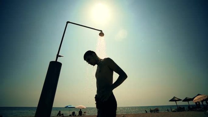 一个年轻人在海滩淋浴下洗头，慢动作