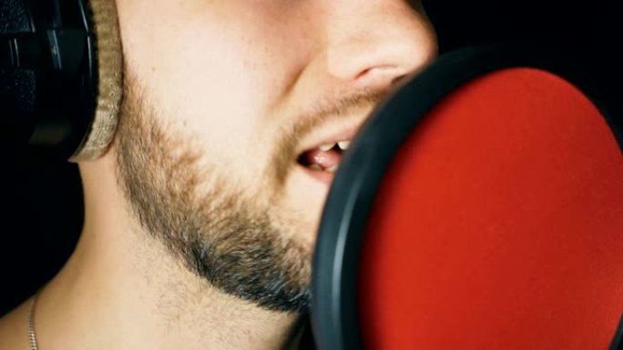 在sound studio演唱的男歌手之口。无法辨认的人录制新歌。留着胡子的家伙对着麦克风唱歌。创意