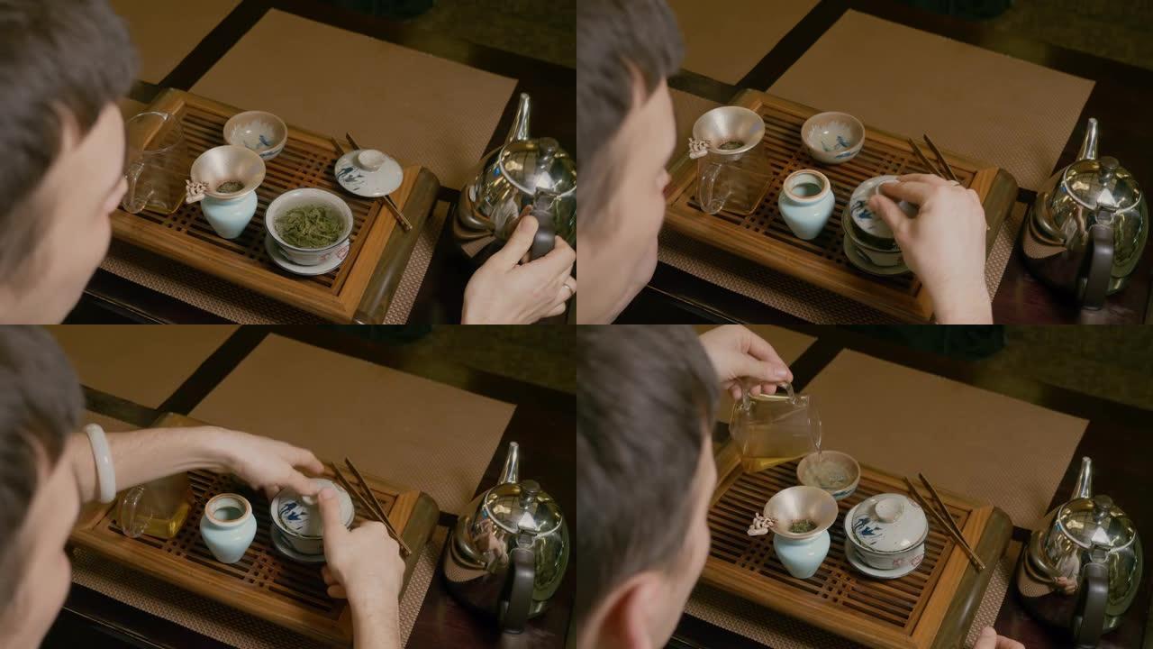 茶师在木桌上用绿茶将热水从水壶倒入盖湾