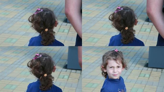一个小女孩的后视图将头转向相机并斜视