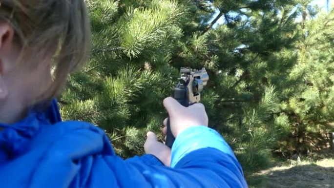 一个拿着枪的少年暗示了一个目标。少女射击气动手枪。手握气动左轮手枪。特写。