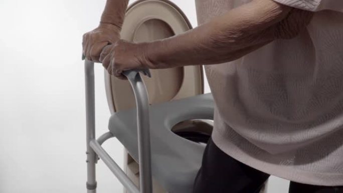 使用移动马桶座椅椅的老年妇女