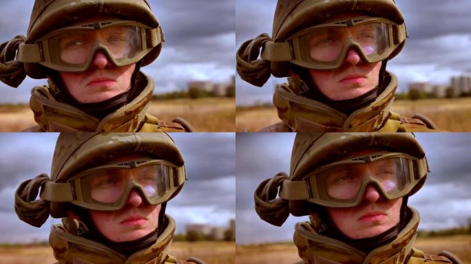 严肃果断的脸戴着头盔的白种士兵站在原地环顾四周，孤立在麦田的背景下，后面是黑暗的天空