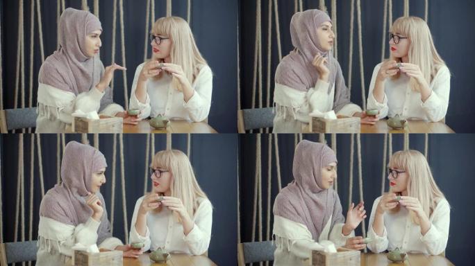 两名穆斯林和白人妇女坐在咖啡馆里聊天，喝茶。