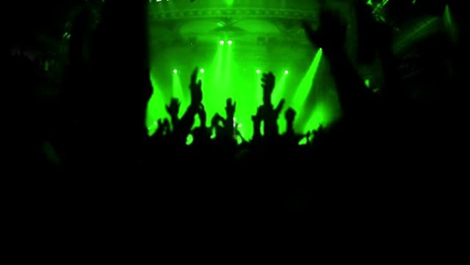 绿色闪烁: 摇滚音乐会上欢呼人群的实时视频放慢了一秒钟，然后恢复