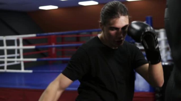 跆拳道击中拳击梨。一个愤怒的拳击手戴着黑色手套在拳击袋里打了一拳。在健身房锻炼