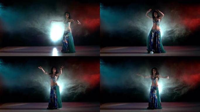 美丽苗条的女人肚皮舞性感跳舞蓝色，红色，烟雾，慢动作
