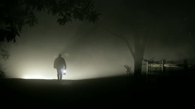 男人在漆黑的夜晚走进雾中
