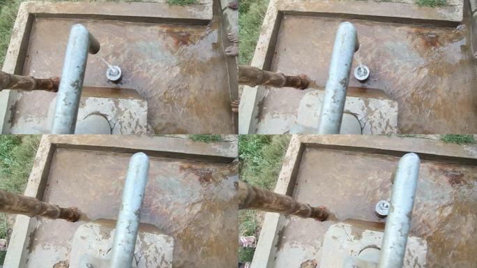 在印度慢动作中，水从手泵中流出，进入水桶
