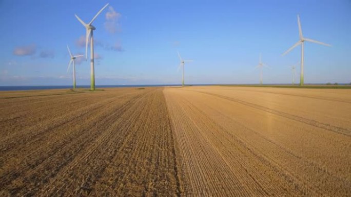 德国费马恩-石勒苏益格-荷尔斯泰因岛上带有拖拉机犁田和风力涡轮机的农业玉米田的鸟瞰图