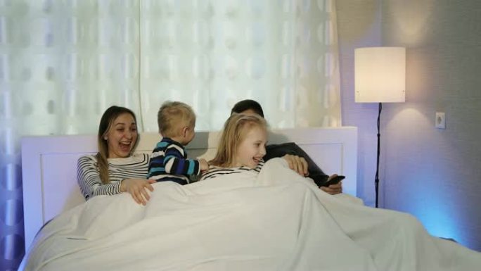 幸福的一家人躺在床上看电视。