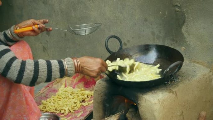 印度妇女在土坯炉子上烹饪传统小吃。