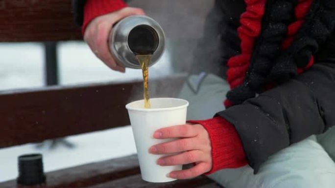 女人将热水瓶中的茶倒入杯子