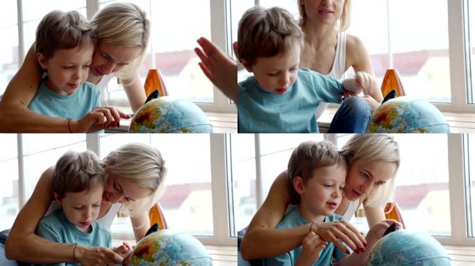 一位迷人的白种人母亲用地球仪向她的小儿子展示世界各国。