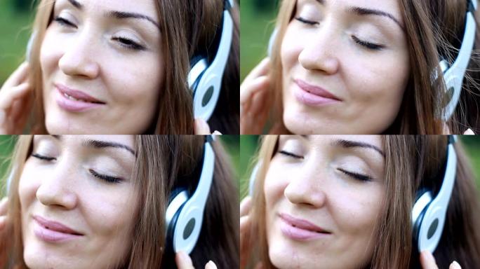 女人在户外闭着眼睛戴着耳机听音乐。一个美丽的特写女孩的肖像。