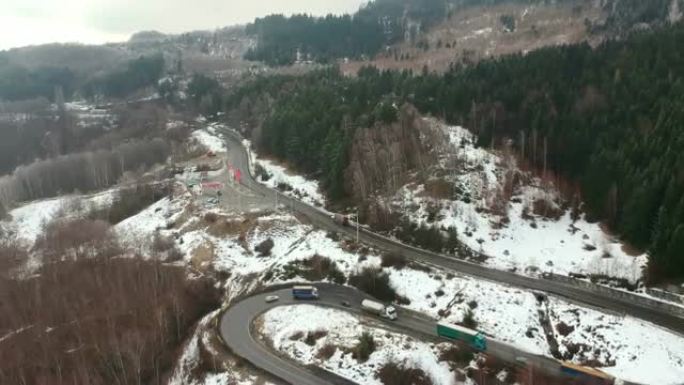 卡车和汽车在罗马尼亚Ciucas山区缓慢穿越危险的弯道和转弯，在冬季条件下，鸟瞰图