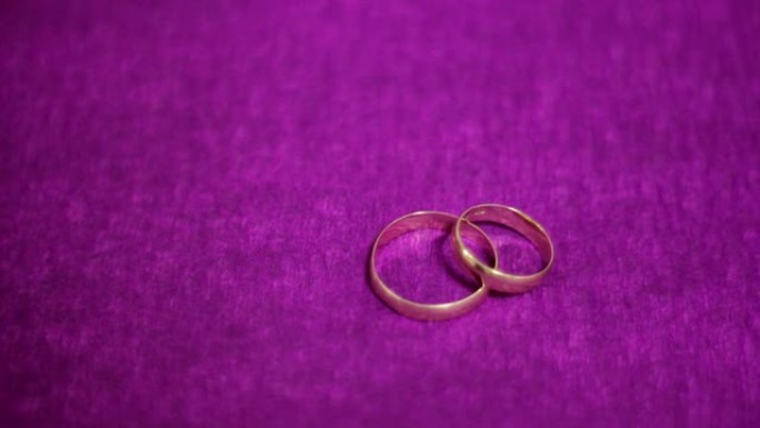 深紫色背景上的两个漂亮的结婚戒指