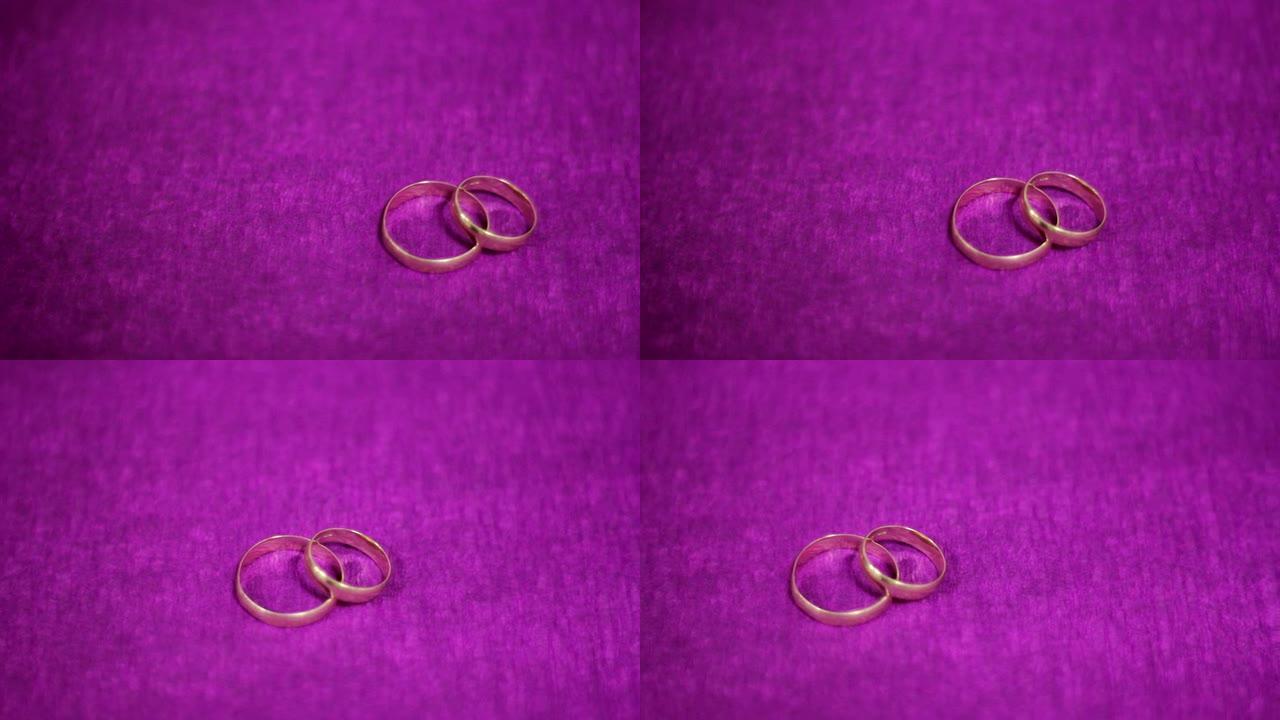 深紫色背景上的两个漂亮的结婚戒指