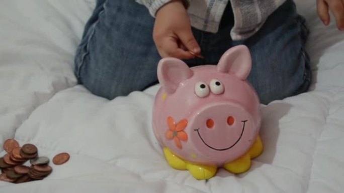 可爱的两岁男婴玩存钱罐，把硬币放在里面