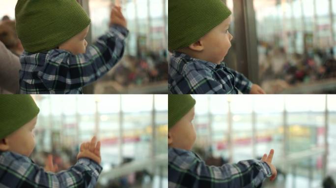 商场里的宝贝透过玻璃看着人。这个男孩戴着一顶绿色针织帽。惊讶地看着相机，孩子们的发展