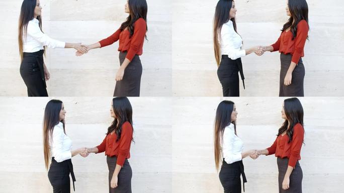 两个时尚的女人在户外握手