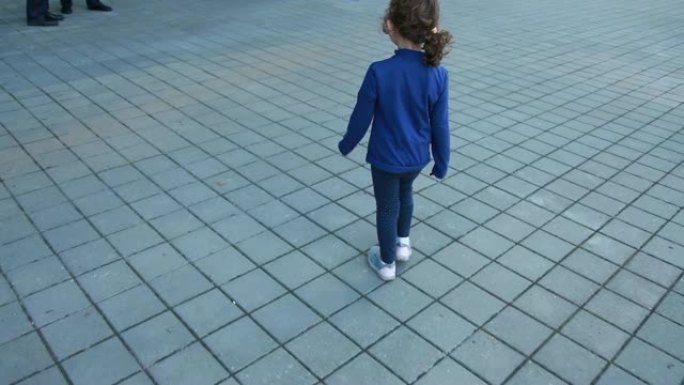 小女孩独自走在街上的后视