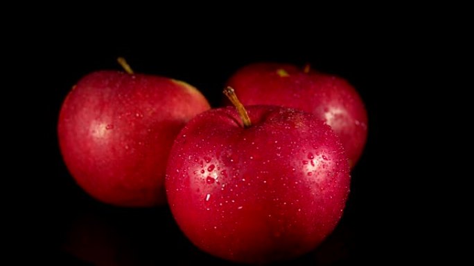 湿红苹果正在黑色背景上转动。